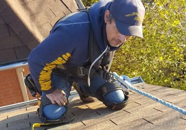 Toronto roofer in a full safety harness repairing wind damage on a steep roof &mdash; Right Choice Roofing and Repair