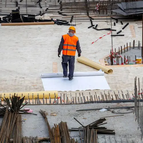 Commercial flat roof replacement in Toronto &mdash; worker in an orange safety vest rolling single-ply membrane &mdash; Right Choice Roofing and Repair.