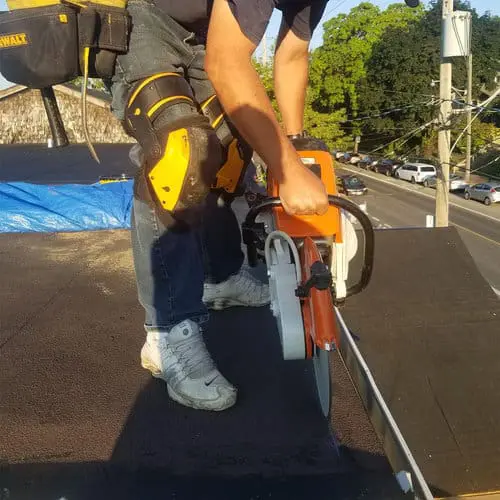 Toronto flat roof replacement &mdash; roofer using a cut-off saw on a residential flat roof by Right Choice Roofing and Repair.