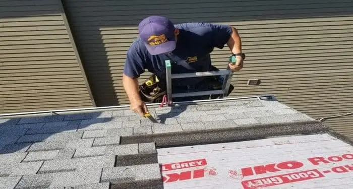 Harnessed roofer aligns a new asphalt shingle course during Toronto roof maintenance&mdash;roof repair and roof replacement, with slate roofing expertise by Right Choice Roofing and Repair.
