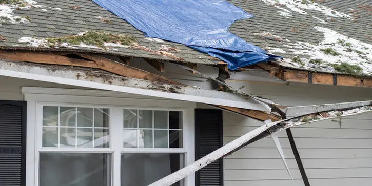 Storm-damaged Toronto roof covered with a blue tarp for emergency protection before professional roof repair.