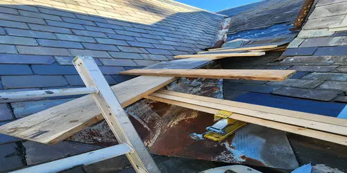 Slate roof repair in progress on a Toronto home, showing removed slate tiles and exposed flashing during professional roof repair.