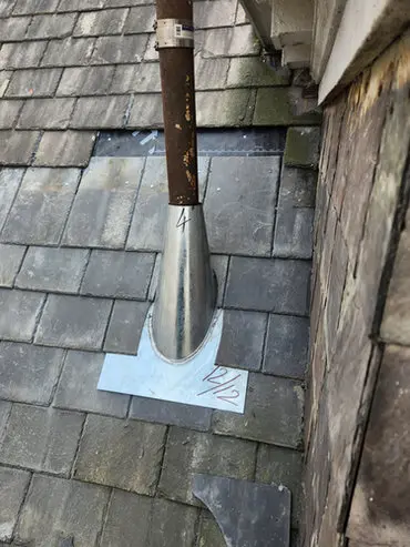 Slate roof repair in Moore Park, Toronto showing new metal flashing installed around a vent pipe to stop a leaking slate roof.