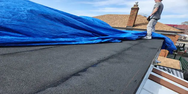 Temporary emergency roof repair on a Toronto flat roof using a blue tarp to protect against active leaks and weather exposure.