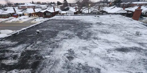Snow-covered flat roof on a Toronto home, showing winter conditions where flat roof snow removal and ice dam prevention are needed.