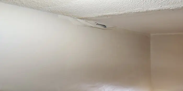 Interior ceiling damage in a Toronto home showing peeling paint and moisture stains caused by an ice dam roof leak.