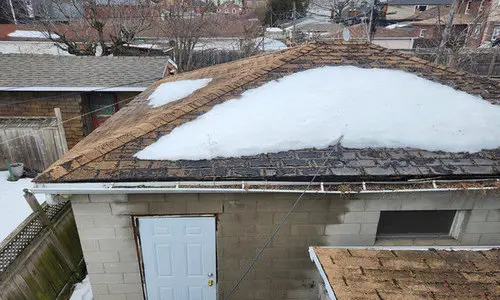 Damaged roof shingles from winter weather showing lifting and wear from freeze-thaw cycles