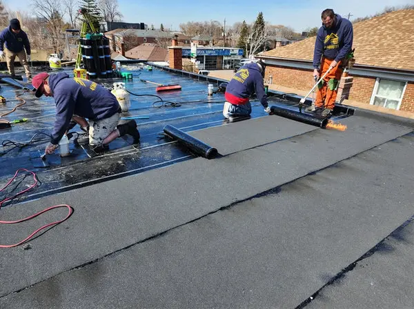 Right Choice Roofing and Repair crew installing modified bitumen flat roof replacement using torch down method on Toronto commercial property with four technicians actively working on membrane installation