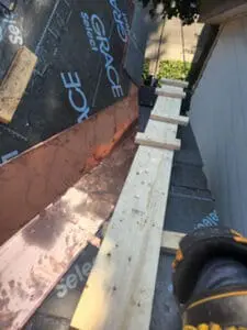 Progress photo showing engineered bridgework and wood plank work platform on metal jacks positioned alongside copper drip edge and Grace Select underlayment at gable edge during slate roof replacement in Harbord Village Toronto by Right Choice Roofing and Repair