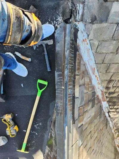 Before photo of rusted painted Ridge Cap Flashing along a brick wall on a Rosedale Toronto Slate Roof prior to copper replacement