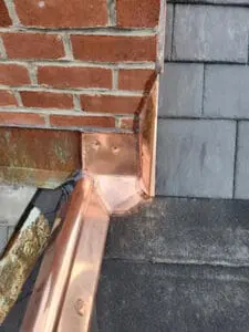 Final finish hand-fabricated copper Flashing at a brick Chimney corner with Counter Flashing tucked into the mortar and sistered apron detail on a Rosedale Toronto heritage Slate Roof by Right Choice Roofing and Repair