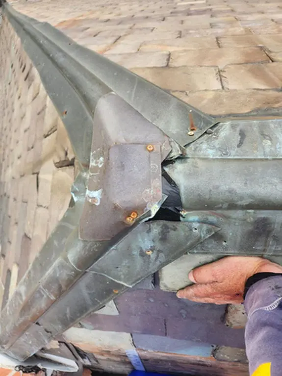 Old copper Ridge Cap that was not installed correctly being lifted on a Rosedale Toronto heritage Slate Roof showing poor fabrication, wrong fasteners, and galvanic corrosion before replacement by Right Choice Roofing and Repair