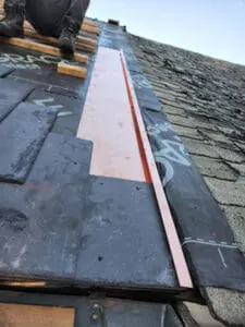 Progress photo looking down slope showing full length of custom fabricated copper semi-detached separation transition flashing running along property line between new slate roof and neighbouring attached roof in Harbord Village Toronto by Right Choice Roofing and Repair