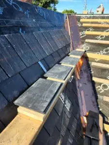 Progress photo showing custom copper valley flashing installed between two slate roof sections with new slate tiles cut and fitted tight to valley during slate roof replacement in Harbord Village Toronto by Right Choice Roofing and Repair
