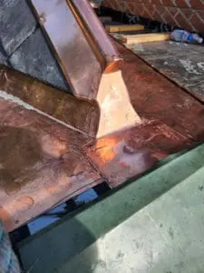 Progress photo showing custom fabricated copper ridge cap closure fully installed at junction between slate roof and copper flat roof during slate roof replacement in Harbord Village Toronto by Right Choice Roofing and Repair