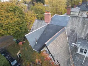 Side aerial view of completed natural Slate Roof and flat Roof replacement on a Rosedale Toronto heritage home with new copper Flashing and Chimneys