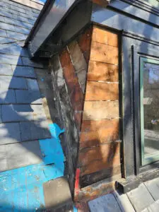 Slate tile removal on a Toronto dormer reveals the wood board substrate for inspection and restoration.