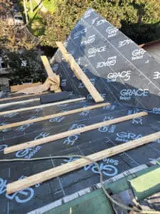 Progress photo looking up main slope from flat roof showing Grace Select underlayment installed with 2x4 step ups and wood plank work platform on metal jacks ready for slate installation in Harbord Village Toronto by Right Choice Roofing and Repair