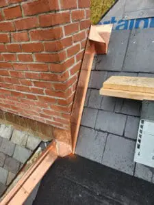 Custom fabricated copper Counter Flashing with sistering Ridge Cap hand-formed at the corner of a brick Chimney on a Rosedale Toronto heritage Slate Roof by Right Choice Roofing and Repair