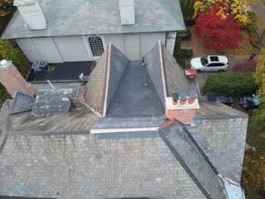 Close aerial view of a finished natural Slate Roof and flat Roof replacement in Rosedale Toronto showing new copper Valley Flashing and copper Ridge detail