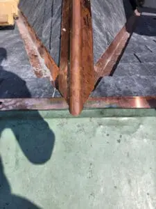 Progress photo showing custom fabricated copper dormer ridge cap extension tying into copper flat roof below with new slate tiles on both dormer faces during slate roof replacement in Harbord Village Toronto by Right Choice Roofing and Repair