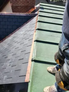 Final photo showing completed slate roof replacement with new slate tiles and copper drip edge along eave line with copper flat roof in foreground and Frank Gillis inspecting finished job in Harbord Village Toronto by Right Choice Roofing and Repair