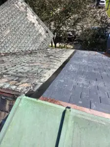 Final photo showing completed aluminum cap closure running along full property line separation between new slate roof and neighbouring shingle roof with copper flat roof in foreground in Harbord Village Toronto by Right Choice Roofing and Repair