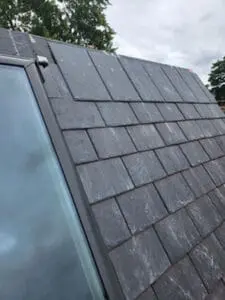 Progress photo showing new slate tiles being installed on main slope alongside Velux skylight on heritage home in Harbord Village Toronto by Right Choice Roofing and Repair