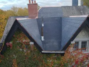 Front aerial view of a completed heritage natural Slate Roof and flat Roof replacement in Rosedale Toronto with copper Valleys, copper Drip Edge, and brick Chimney