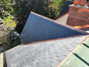 Final photo showing completed heritage slate roof replacement with new natural slate tiles and copper drip edge on full main slope alongside brick chimney and copper flat roof in Harbord Village Toronto by Right Choice Roofing and Repair