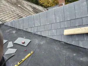 Precision-cut natural Slate tiles staged with Slate cutter and level on a Rosedale Toronto flat Roof with completed Dormer Slate courses in the background by Right Choice Roofing and Repair