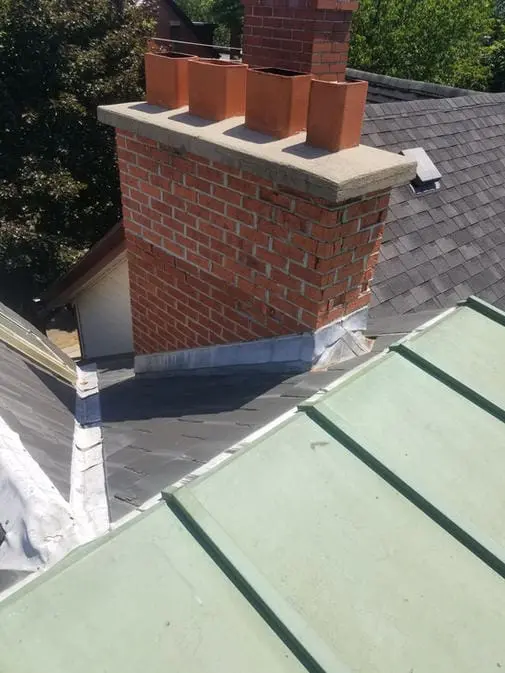 Before restoration by Right Choice Roofing and Repair: A large brick chimney with clay flues and grey lead flashing on a slate roof in Harbord Village, Toronto.