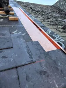 Progress photo showing custom fabricated copper semi-detached separation and transition flashing system installed along property line between slate roof and neighbouring roof in Harbord Village Toronto by Right Choice Roofing and Repair