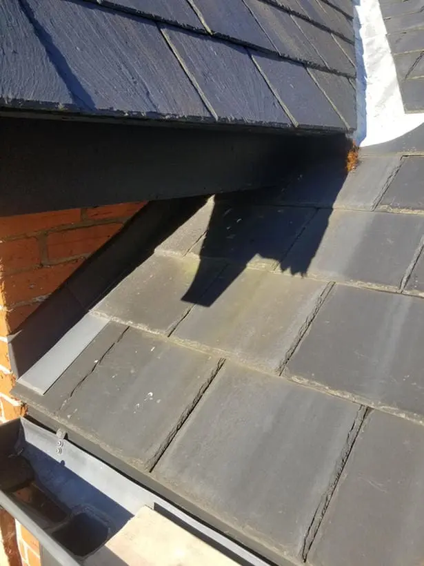Before photo showing worn slate tiles and lead flashing at dormer corner next to brick chimney in Harbord Village Toronto prior to replacement by Right Choice Roofing and Repair