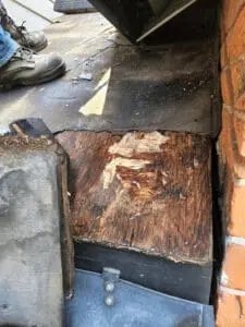 Progress photo showing rotted roof deck boards at chimney base caused by ice dam water infiltration on slate roof in Harbord Village Toronto by Right Choice Roofing and Repair