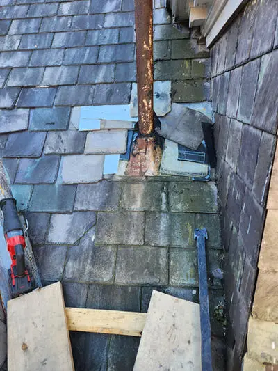 Persistent slate roof leak repair and plumbing exhaust flange replacement with damaged and patched Slate Tiles on a heritage home in Toronto.