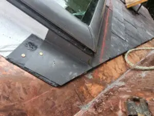 Progress photo showing new slate tiles installed around Velux skylight with custom copper counter flashing fitted tight against skylight frame and copper nails visible in Harbord Village Toronto by Right Choice Roofing and Repair