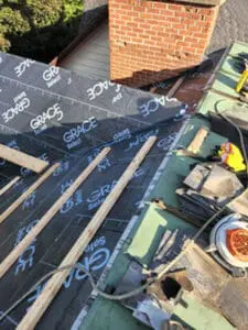 Progress photo from flat roof showing Grace Select waterproofing installed on main slope with 2x4 step ups brick chimney and eave detail visible during slate roof replacement in Harbord Village Toronto by Right Choice Roofing and Repair