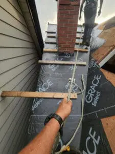 Progress photo showing Toronto slate roofer working on steep slate roof with 2x4 step ups and rope safety line with Grace Select underlayment installed in Harbord Village Toronto by Right Choice Roofing and Repair