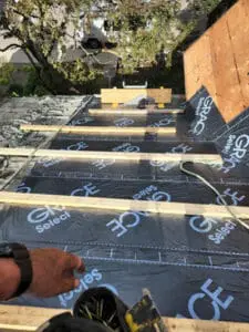 Progress photo showing Frank Gillis nailing 2x4 step ups onto Grace Select underlayment on steep slate roof main slope during slate roof replacement in Harbord Village Toronto by Right Choice Roofing and Repair