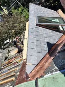 Progress photo from flat roof showing Toronto slate roofing services in action with dormer nearly fully slated Velux skylight fitted and copper valley and drip edge installed in Harbord Village Toronto by Right Choice Roofing and Repair