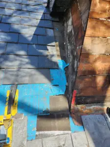 Slate tile removal by Right Choice Roofing and Repair in Toronto to prepare for new copper flashing installation on a dormer sidewall.
