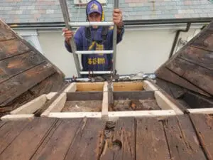 Frank, owner of Right Choice Roofing and Repair, on a ladder at a Rosedale Toronto heritage Slate Roof with new carpentry framing completed and original Slate tiles on either side