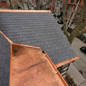Completed slate roof replacement in Toronto showing new natural slate tiles, custom copper valley, copper flat roof and eavestrough installation by Right Choice Roofing and Repair.