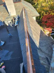New copper Ridge Cap installed on a Rosedale Toronto heritage Dormer sloped Roof with completed natural Slate courses on both sides by Right Choice Roofing and Repair
