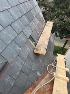 Progress photo showing wood plank work platform on metal jacks positioned on newly installed slate tiles with rope safety line during slate roof replacement in Harbord Village Toronto by Right Choice Roofing and Repair
